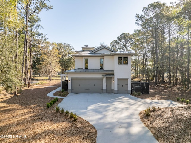view of front of property featuring stucco siding, a standing seam roof, metal roof, an attached garage, and driveway