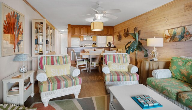 living room featuring hardwood / wood-style flooring, ceiling fan, and wood walls