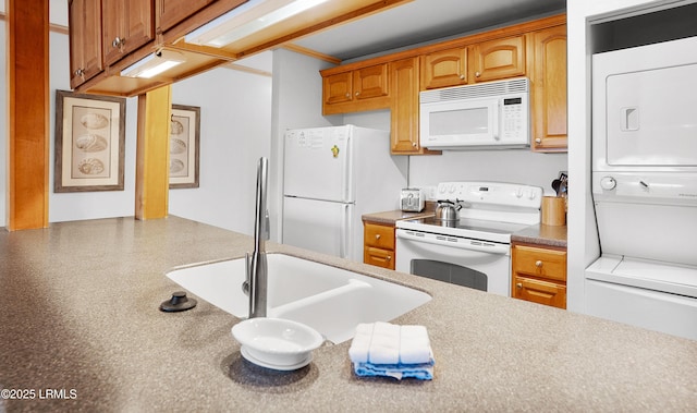 kitchen with stacked washer and dryer, sink, and white appliances