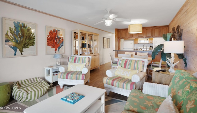 living room with crown molding, wood-type flooring, sink, and ceiling fan