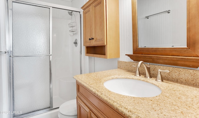 bathroom featuring vanity, toilet, and a shower with door