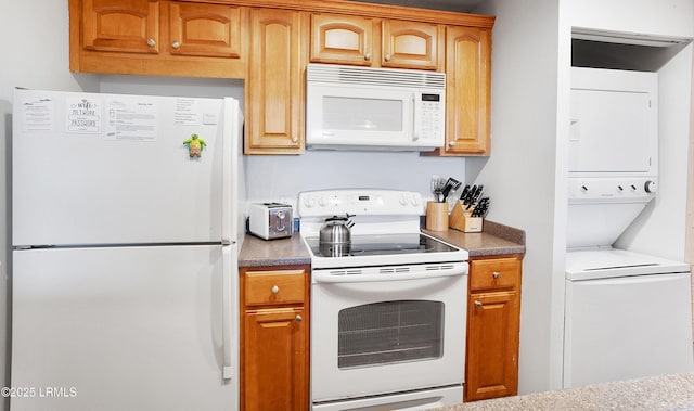 kitchen with white appliances and stacked washer / dryer