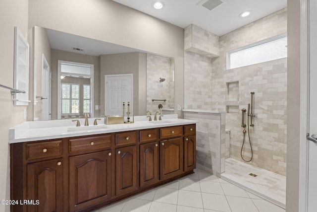 bathroom with tiled shower, vanity, and tile patterned flooring