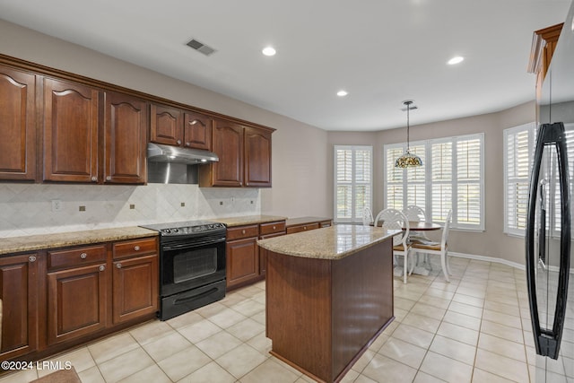 kitchen featuring tasteful backsplash, hanging light fixtures, a center island, light stone counters, and black appliances