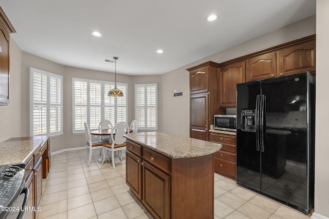 kitchen with decorative light fixtures, a center island, range, light stone counters, and black fridge