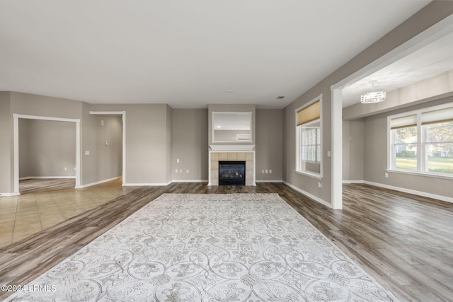 unfurnished living room featuring hardwood / wood-style flooring and a tiled fireplace