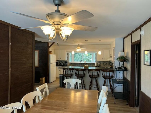 dining area featuring sink, wood-type flooring, and ceiling fan