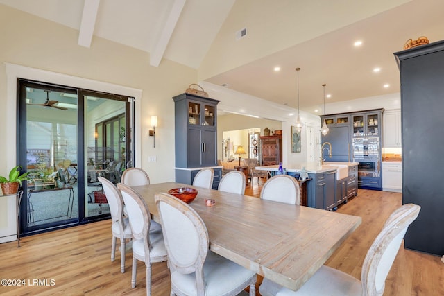 dining area featuring sink, vaulted ceiling with beams, ceiling fan, and light hardwood / wood-style flooring