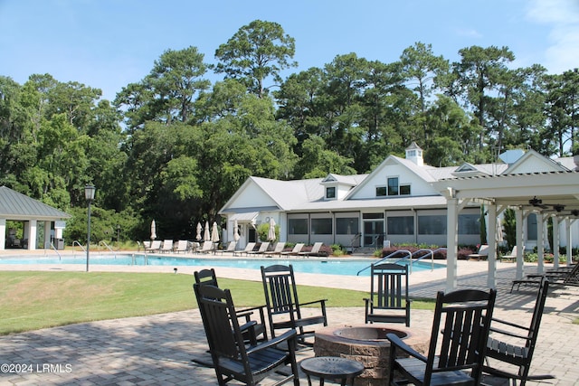 view of swimming pool with a lawn, a pergola, an outdoor fire pit, a patio area, and a sunroom