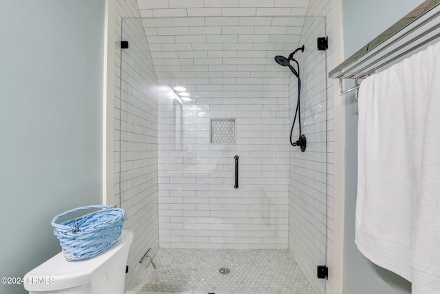 bathroom featuring a shower with door and toilet