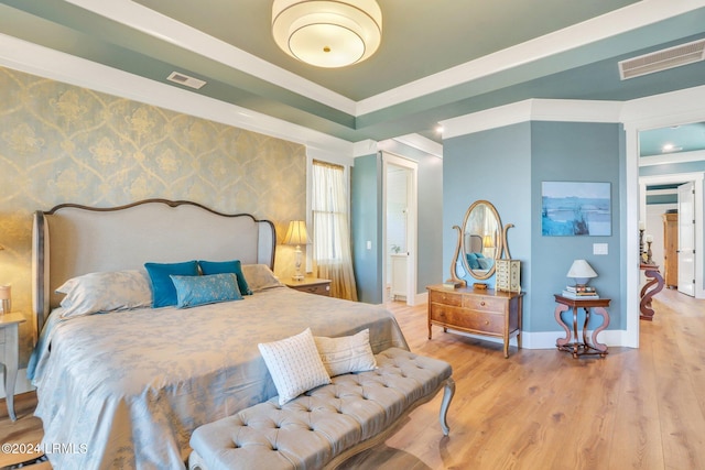 bedroom featuring connected bathroom and light hardwood / wood-style flooring