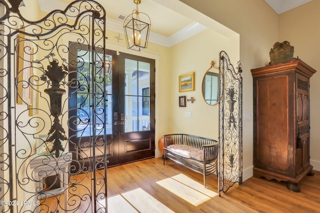 entryway with an inviting chandelier, crown molding, and light hardwood / wood-style flooring