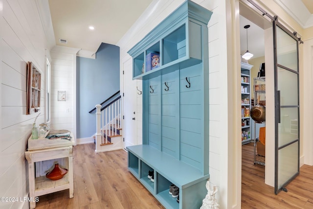 mudroom featuring ornamental molding, a barn door, and light wood-type flooring