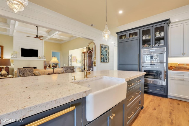 kitchen featuring pendant lighting, double oven, beamed ceiling, coffered ceiling, and light hardwood / wood-style floors