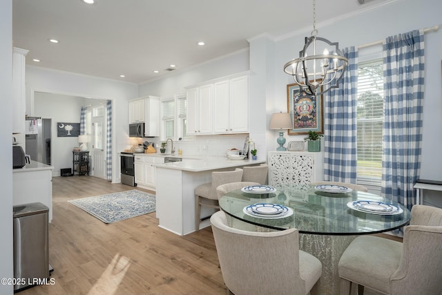 277 Pleasant Point Dr, Beaufort, SC 29907 - kitchen featuring appliances with stainless steel finishes, a chandelier, white cabinets, crown molding, and a sink
