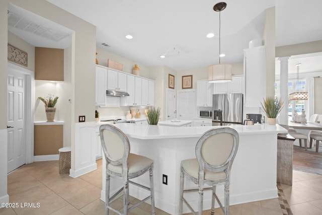 56 Waterford Dr, Bluffton, SC 29910 - kitchen featuring appliances with stainless steel finishes, under cabinet range hood, a kitchen breakfast bar, white cabinets, and recessed lighting