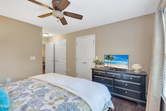 bedroom with multiple closets, dark hardwood / wood-style flooring, and ceiling fan