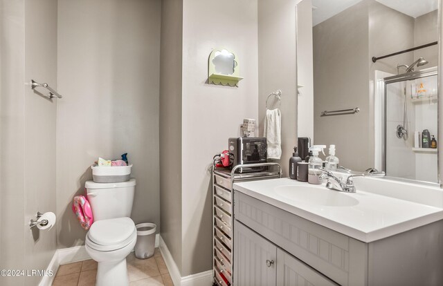 bathroom featuring tile patterned floors, toilet, a shower with door, and vanity