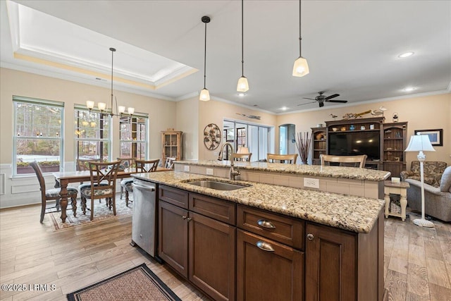 kitchen featuring pendant lighting, sink, stainless steel dishwasher, and light hardwood / wood-style floors