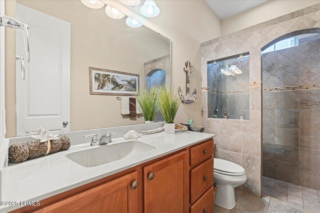 bathroom with vanity, tiled shower, and toilet