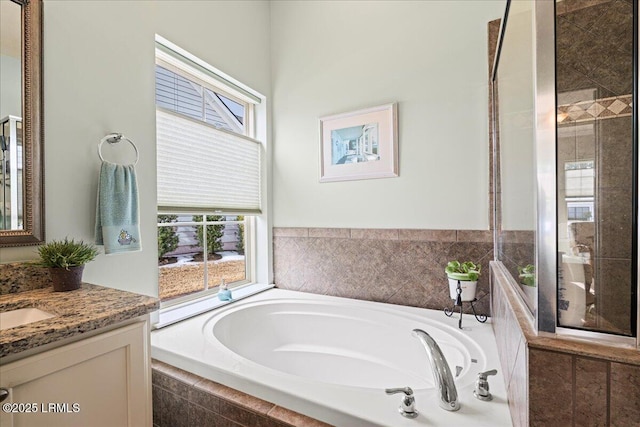 bathroom featuring vanity and tiled bath