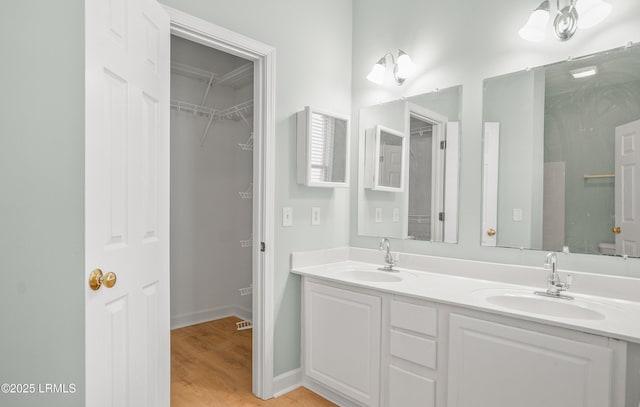 full bathroom with double vanity, wood finished floors, baseboards, and a sink