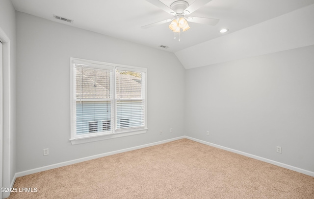 carpeted spare room featuring a ceiling fan, lofted ceiling, baseboards, and visible vents