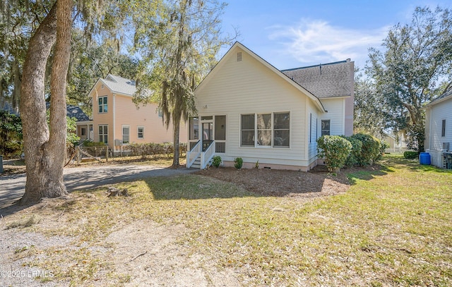 view of front of house featuring roof with shingles, a front lawn, and a sunroom