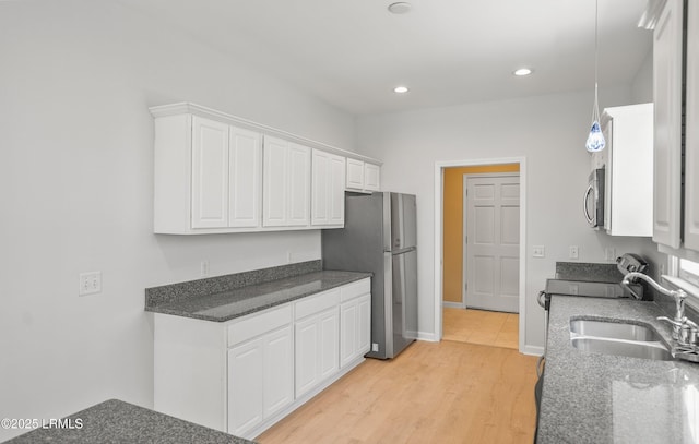 kitchen with light wood-type flooring, recessed lighting, stainless steel appliances, white cabinetry, and a sink