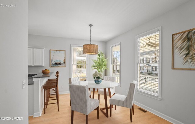 dining space with light wood-type flooring, visible vents, and baseboards