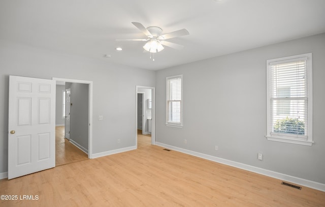 unfurnished bedroom with visible vents, multiple windows, light wood-style flooring, and baseboards