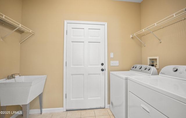 washroom with a sink, light tile patterned flooring, washing machine and dryer, and laundry area