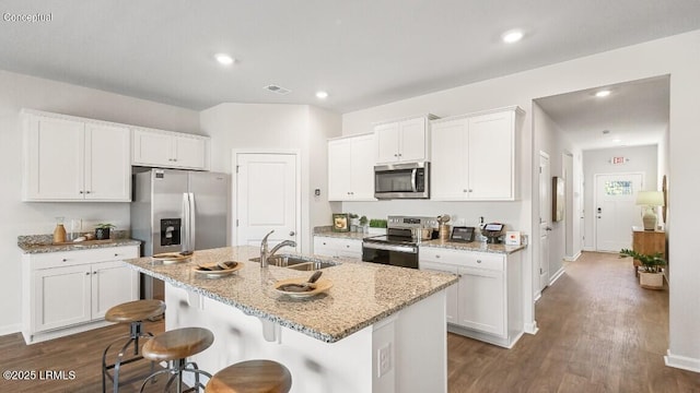 116 Twickenham Loop, Yemassee, SC 29945 - kitchen with dark wood finished floors, a breakfast bar, appliances with stainless steel finishes, white cabinets, and an island with sink