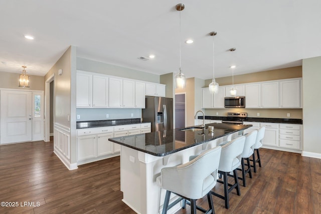 kitchen featuring a sink, hanging light fixtures, stainless steel appliances, white cabinets, and dark wood-style flooring