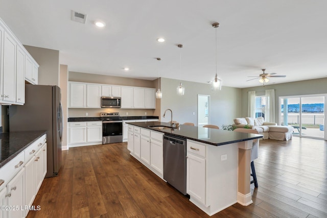 kitchen with a sink, stainless steel appliances, a kitchen breakfast bar, and dark wood finished floors