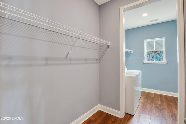 spacious closet featuring dark wood-type flooring, visible vents, and washer and clothes dryer