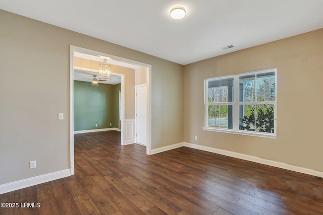 empty room with baseboards, dark wood-style flooring, visible vents, and a chandelier