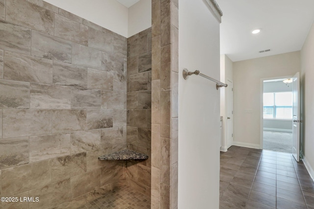 bathroom with baseboards, visible vents, tiled shower, and tile patterned flooring