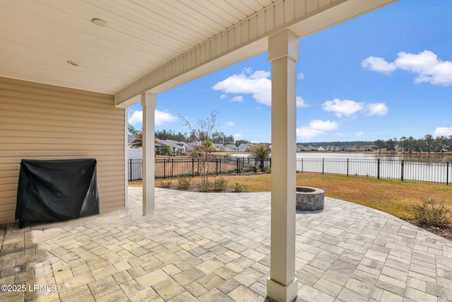 view of patio / terrace with a fenced backyard, a fire pit, a grill, and a water view