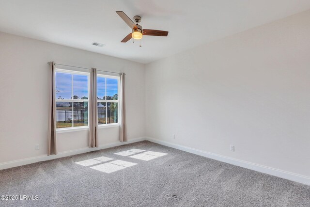 carpeted empty room featuring baseboards, visible vents, and ceiling fan
