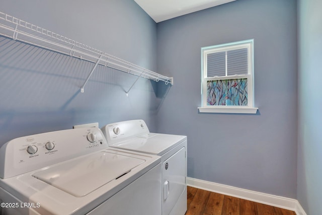 clothes washing area featuring baseboards, washing machine and dryer, laundry area, and dark wood finished floors