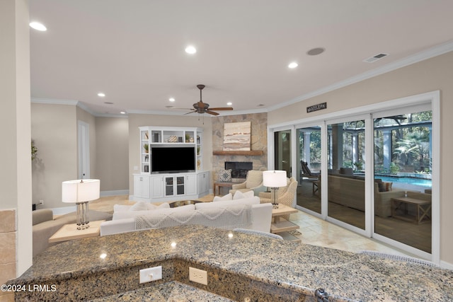 living room with crown molding, ceiling fan, and a fireplace