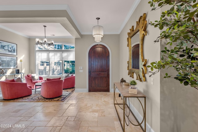 foyer entrance with crown molding and a chandelier