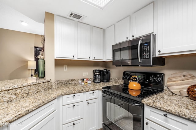 13 Harbourside Ln Unit 7170, Hilton Head Island, SC 29928 - kitchen featuring stainless steel microwave, black range with electric stovetop, white cabinets, and light stone counters