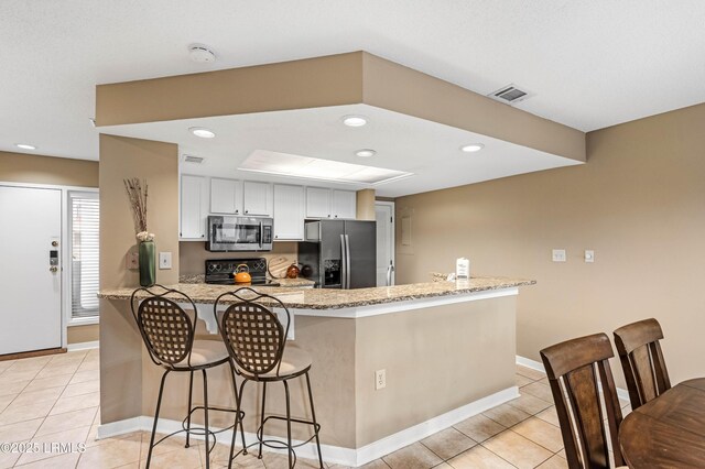 13 Harbourside Ln Unit 7170, Hilton Head Island, SC 29928 - kitchen with fridge with ice dispenser, stainless steel microwave, a breakfast bar area, light tile patterned floors, and recessed lighting