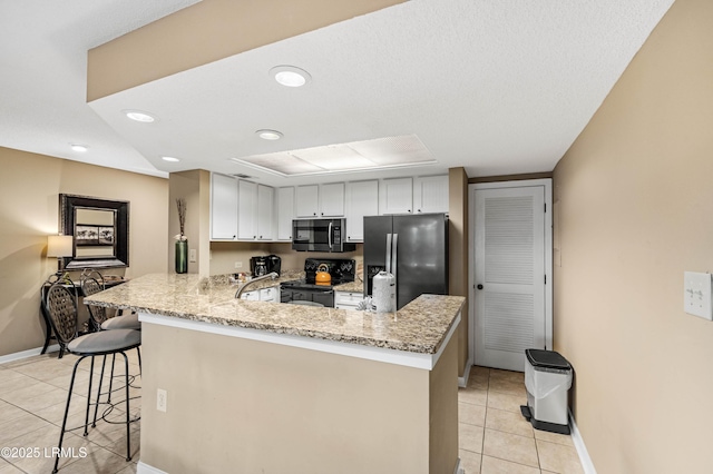 13 Harbourside Ln Unit 7170, Hilton Head Island, SC 29928 - kitchen featuring appliances with stainless steel finishes, light tile patterned floors, a peninsula, a kitchen breakfast bar, and light stone counters