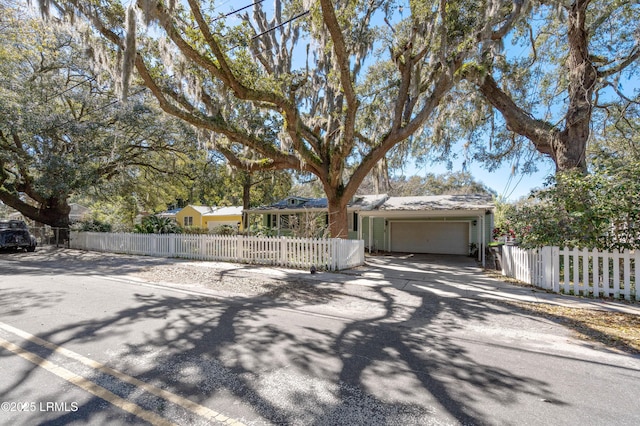 view of front facade featuring an attached garage, driveway, a fenced front yard, and metal roof