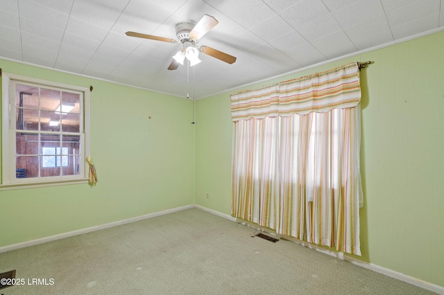 carpeted empty room with visible vents, baseboards, and ceiling fan