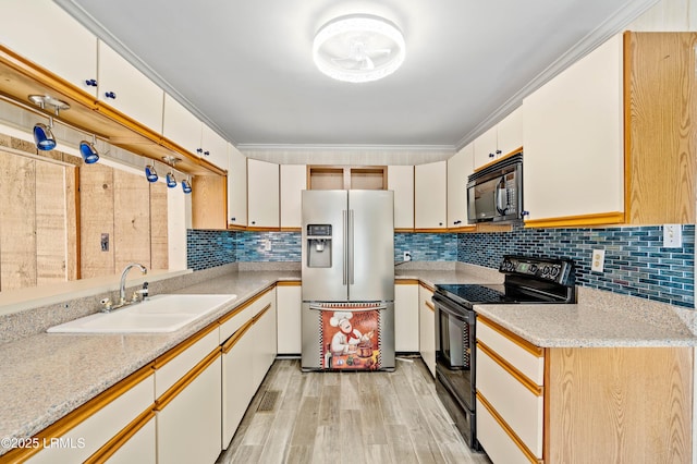 kitchen featuring crown molding, light wood-type flooring, decorative backsplash, black appliances, and a sink