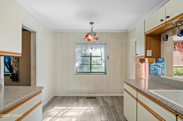 dining space with crown molding, light wood-style flooring, visible vents, and a wealth of natural light